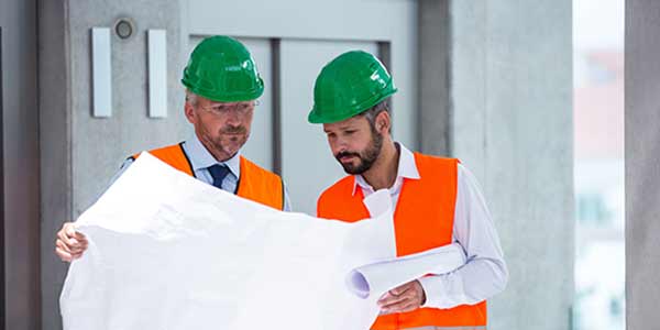 Two architects on site, looking at electrical schematics.
