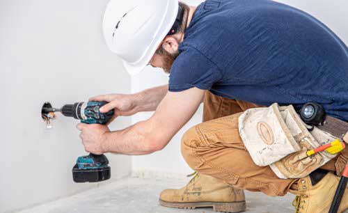 Electrician drilling hole for socket.